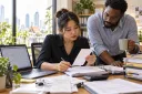A bookkeeper checks document details extracted by AI against paper vouchers.
