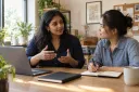 A business owner describing her services while a colleague takes notes.