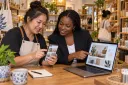 A shop owner and digital advisor compare a social media page with the shop's own website.