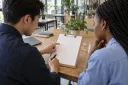 Two colleagues reviewing a blank project checklist together at an office table.